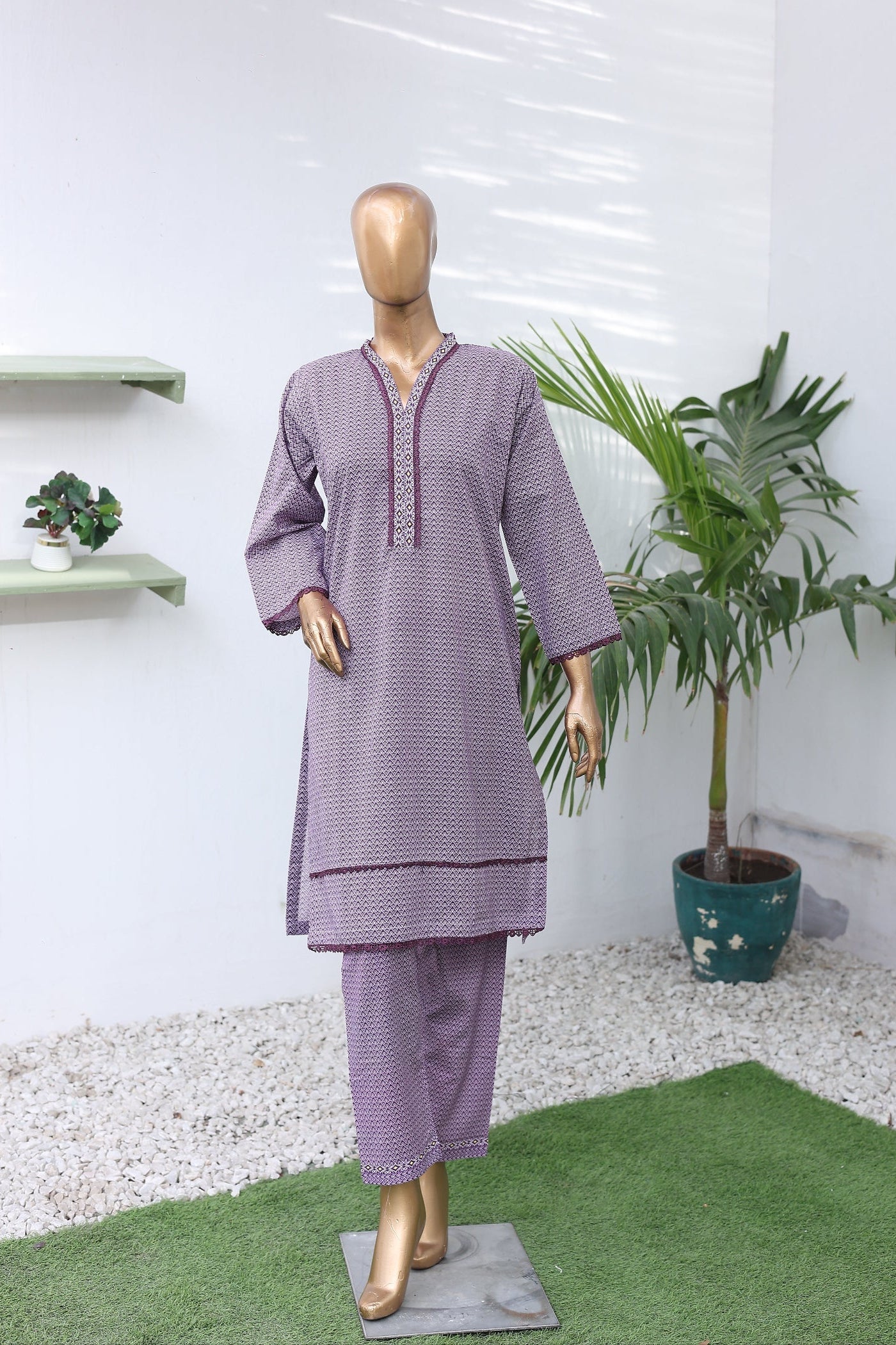 Mannequin wearing a purple outfit with a white background and plant