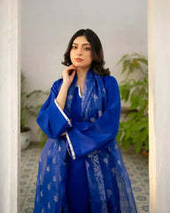 Woman wearing a royal blue traditional outfit with floral patterns indoors.