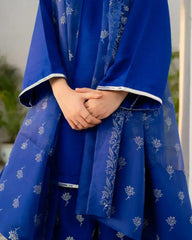 Royal Blue traditional outfit with white floral patterns, held by hands against a blurred background.