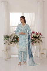 ZARNAZ - Woman in a light blue floral traditional outfit standing in a decorated room with flowers.