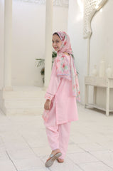 Woman in a pink traditional outfit with floral patterns indoors.