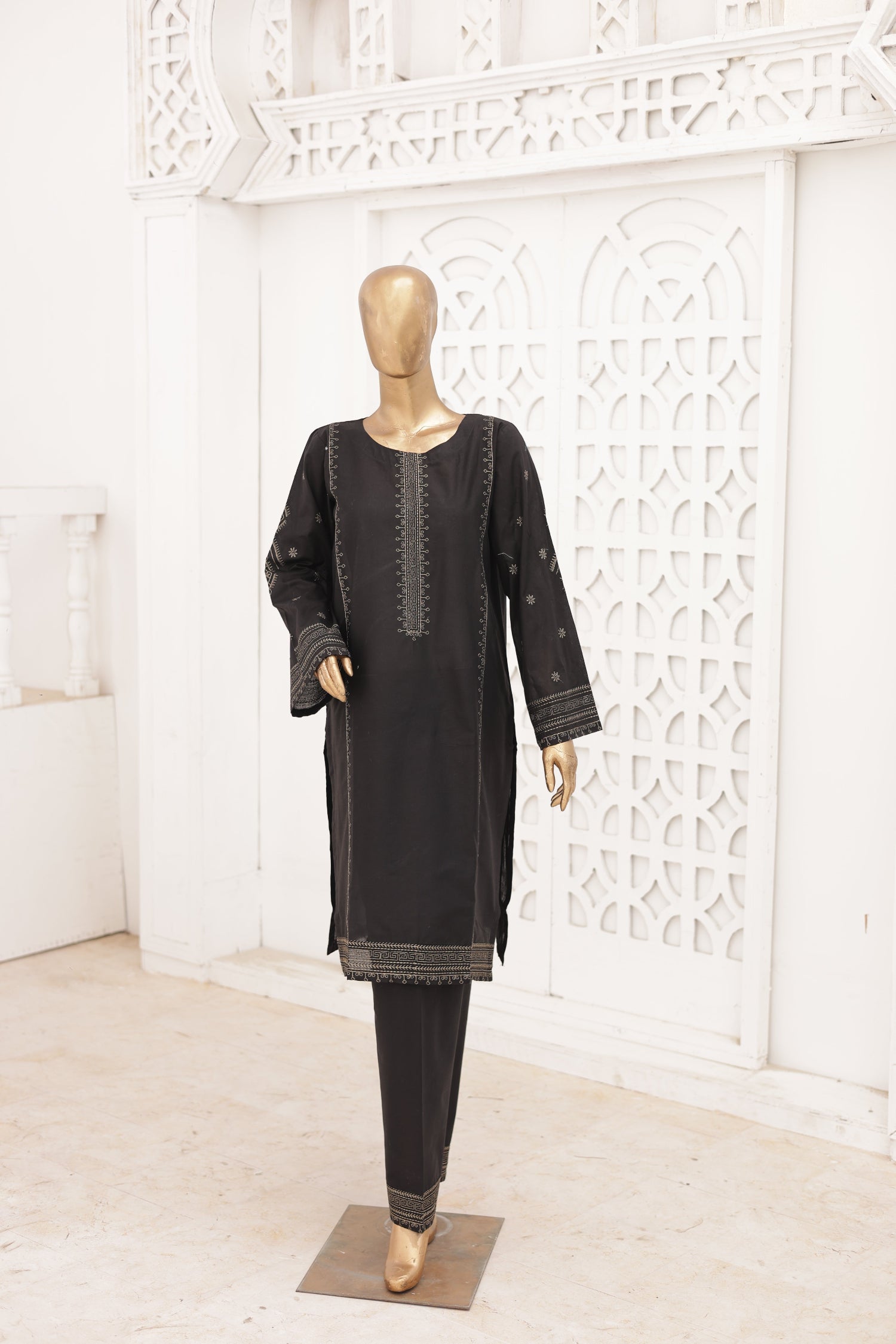 Black traditional outfit on a mannequin against a white decorative wall.
