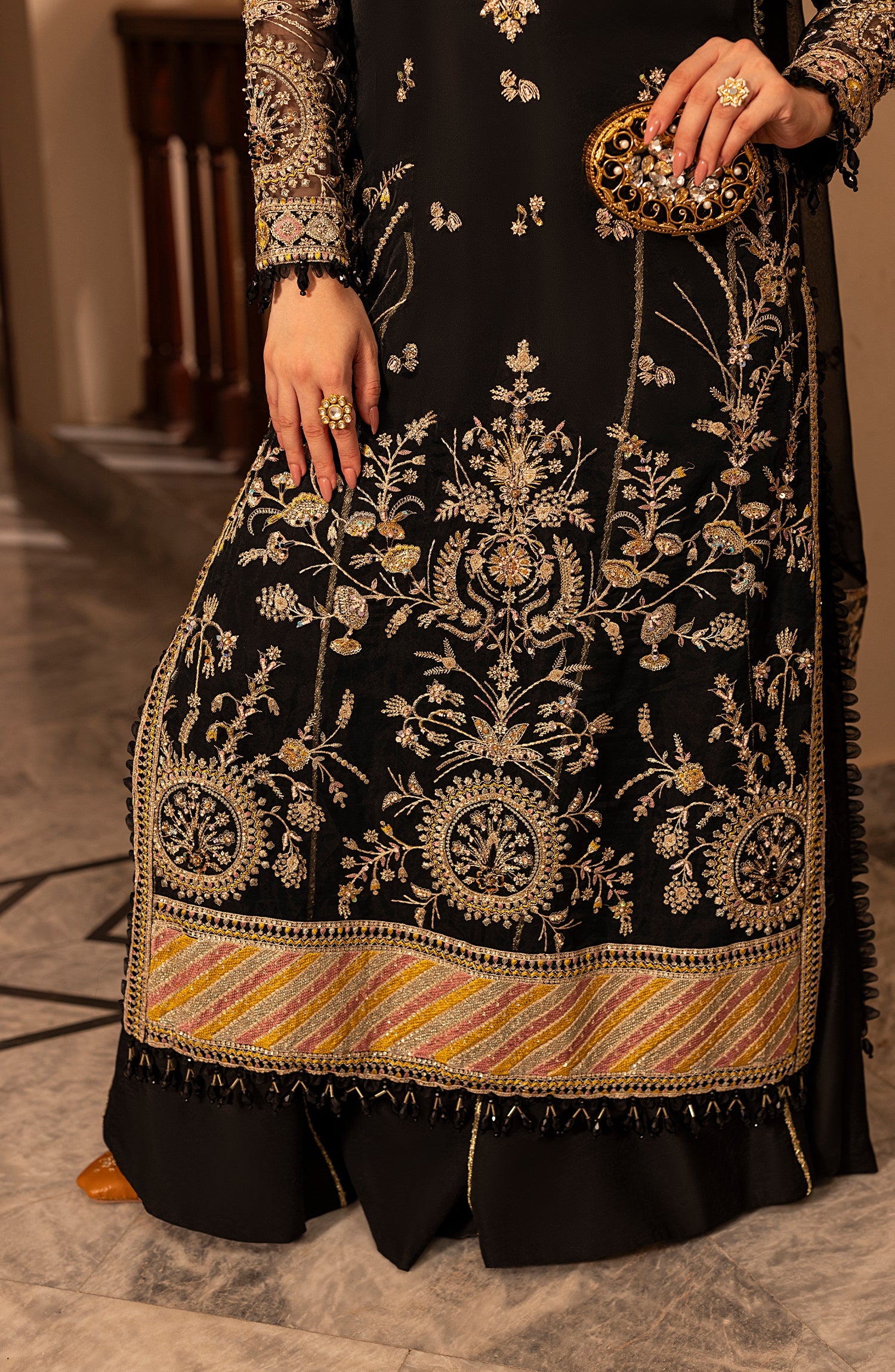 Black embroidered traditional outfit with gold details on a neutral background