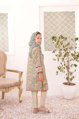 Child wearing a colorful traditional outfit in a room with a chair and plant.