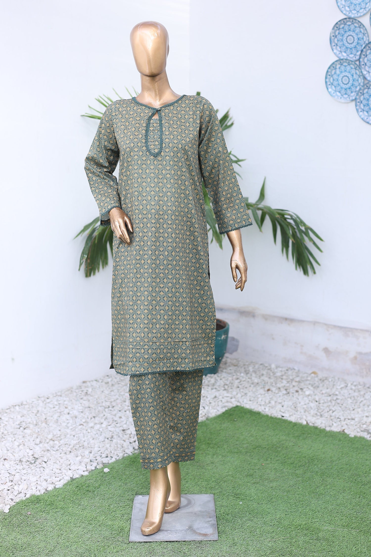 Mannequin wearing a green patterned dress with decorative elements on a white background