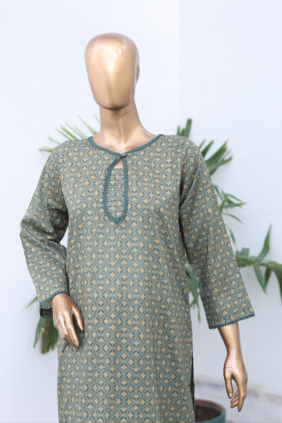 Mannequin wearing a green patterned dress with decorative plates in the background.