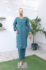 Mannequin wearing a blue patterned outfit in a room with plants and shelves.