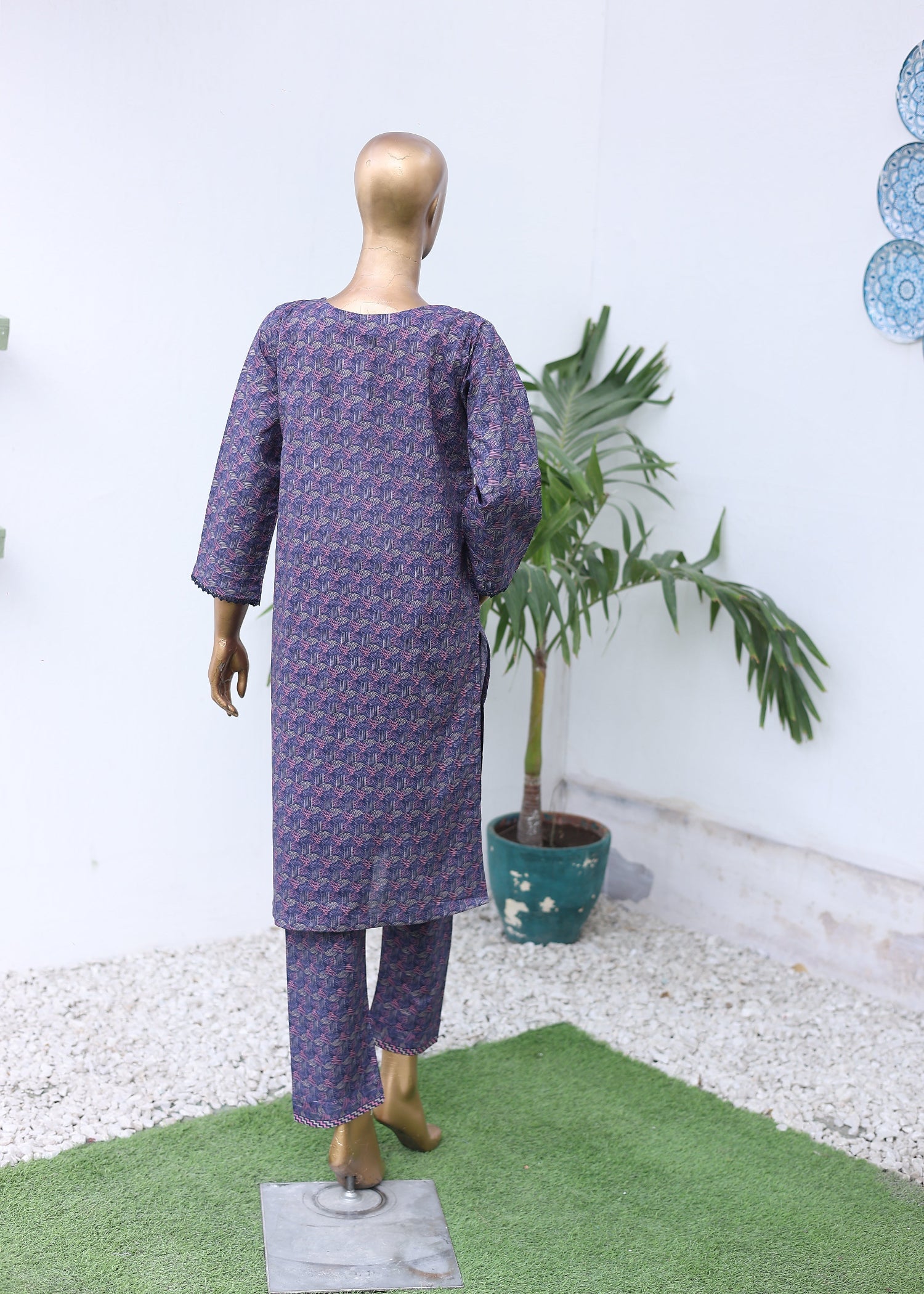 Mannequin wearing a purple patterned outfit with a potted plant on a white and green striped background