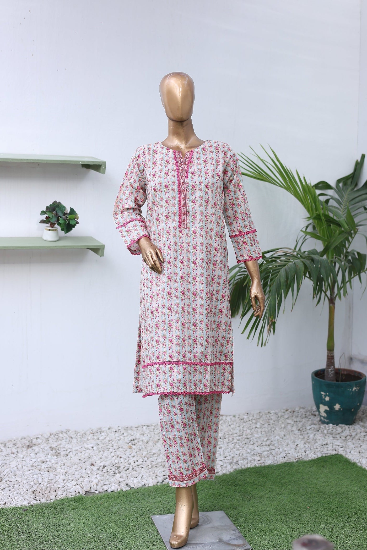 Mannequin wearing a red and white patterned dress on a white background with green plants.
