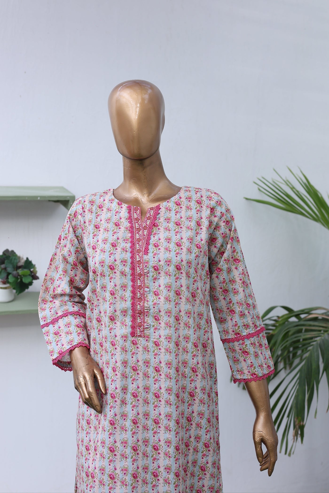 Mannequin wearing a floral dress with pink accents on a white background