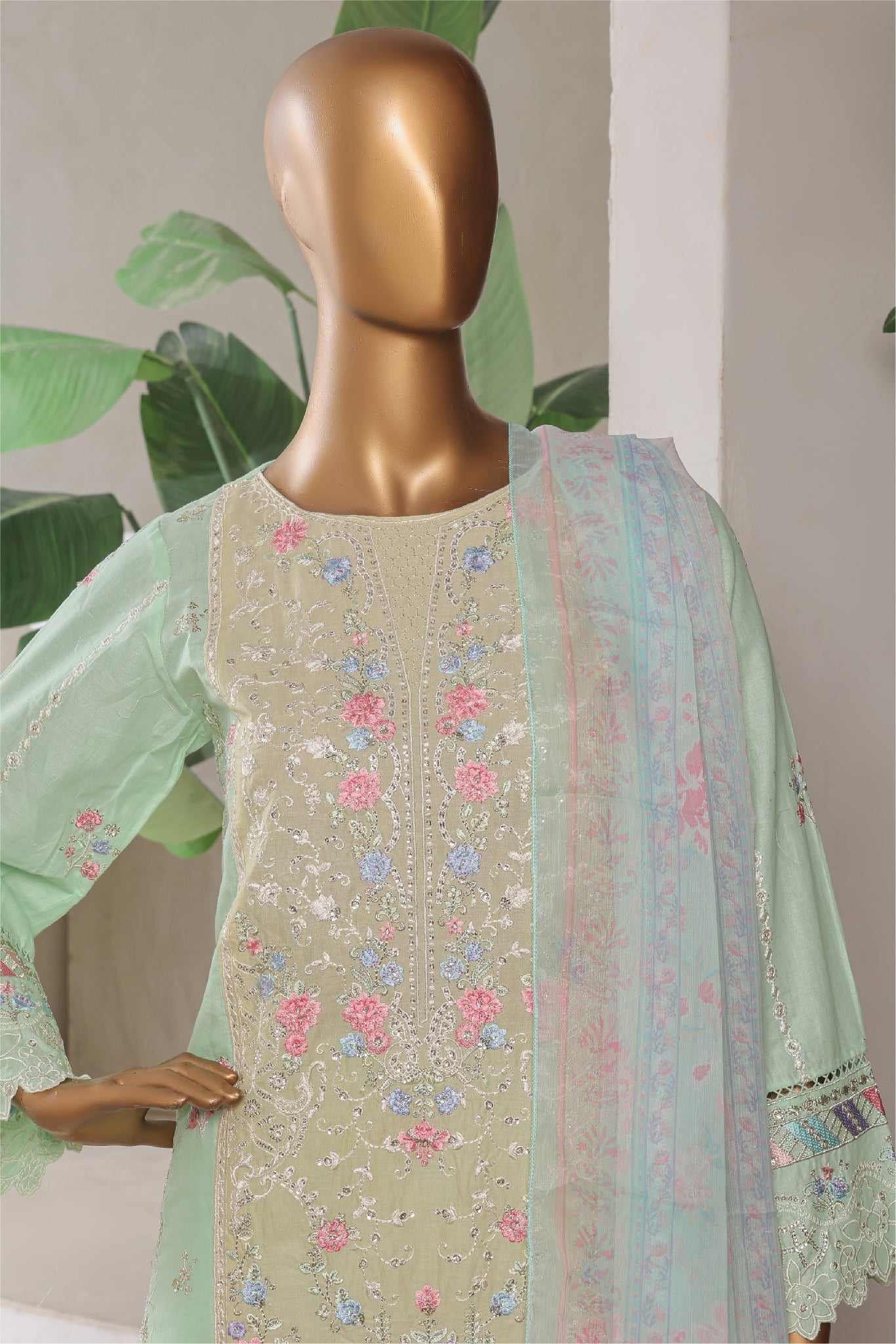 Mannequin wearing a light green embroidered outfit with a floral pattern against a neutral background.