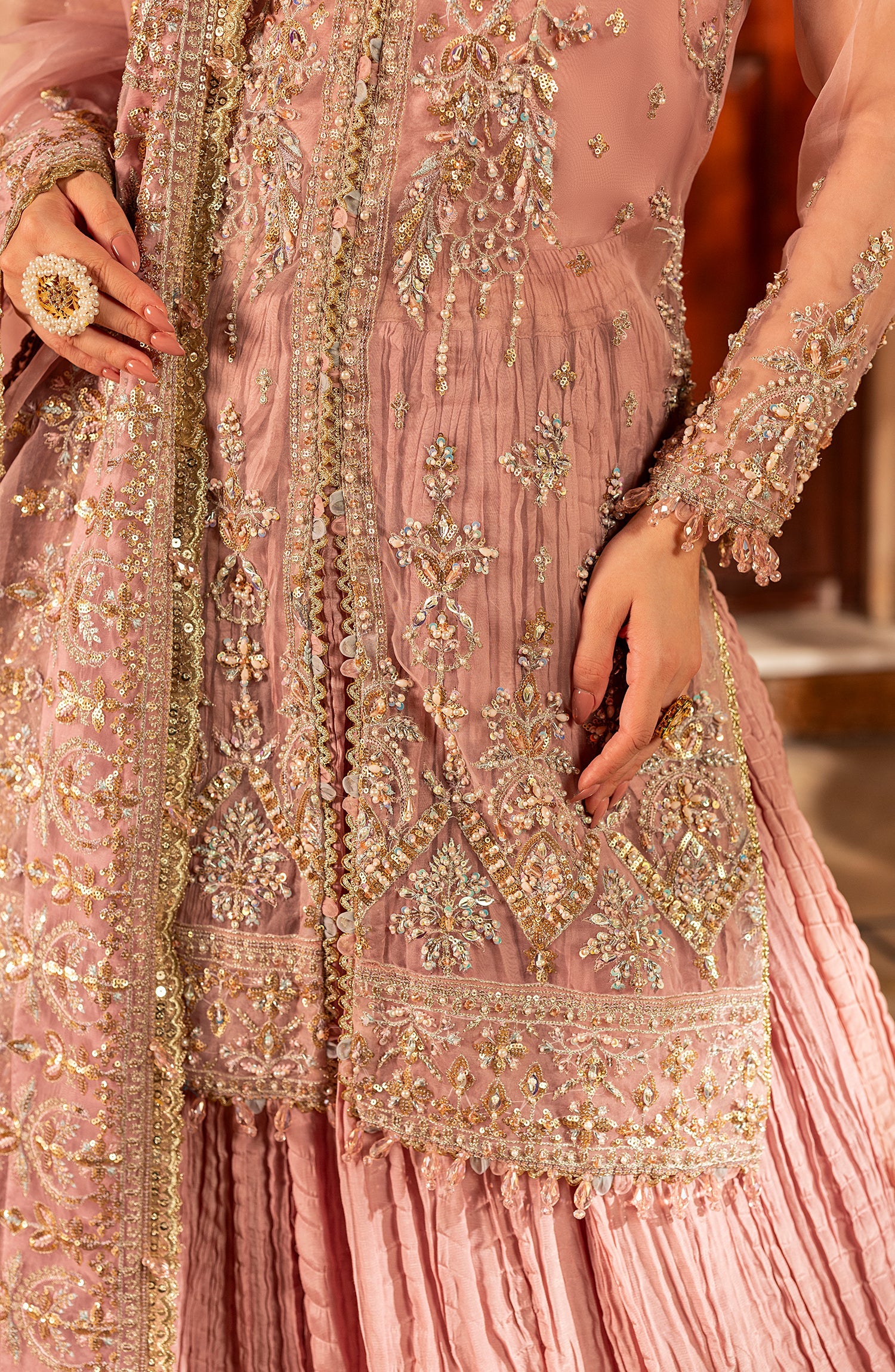 Close-up of a pink embroidered traditional outfit with gold details.