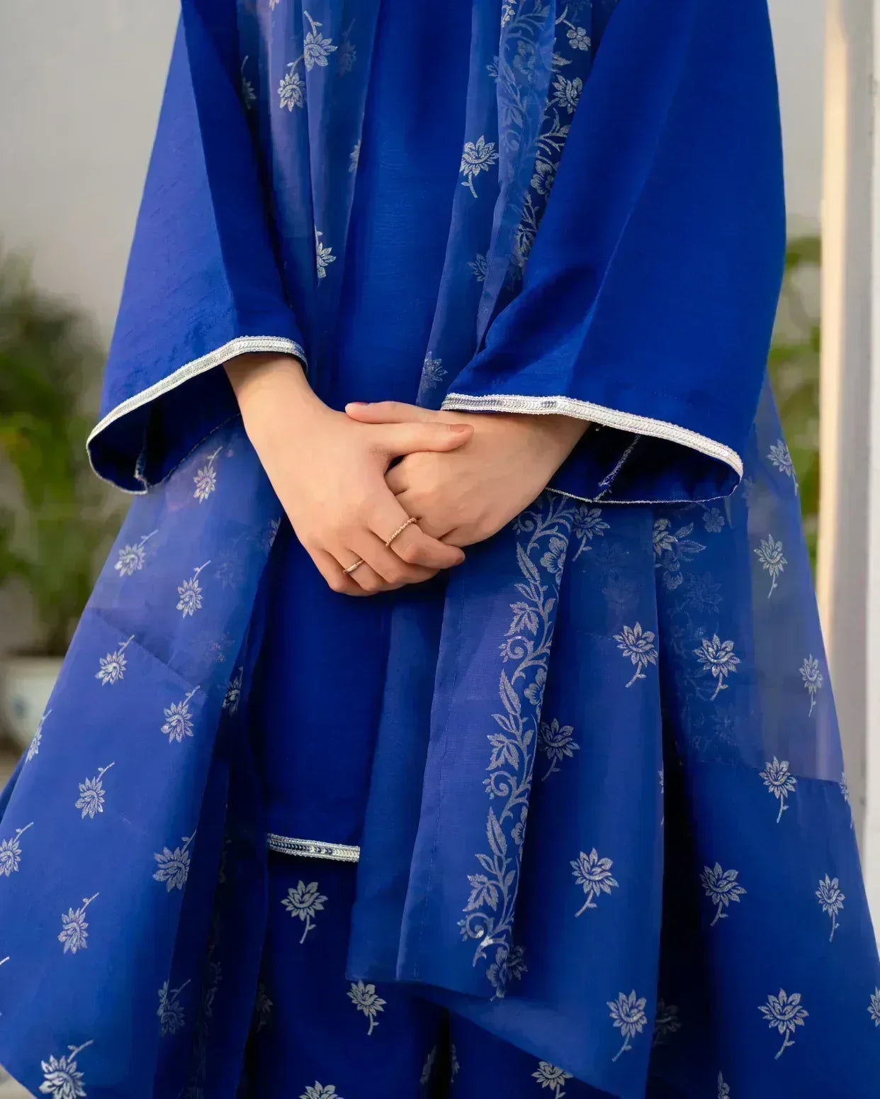Royal Blue traditional outfit with white floral patterns, held by hands against a blurred background.