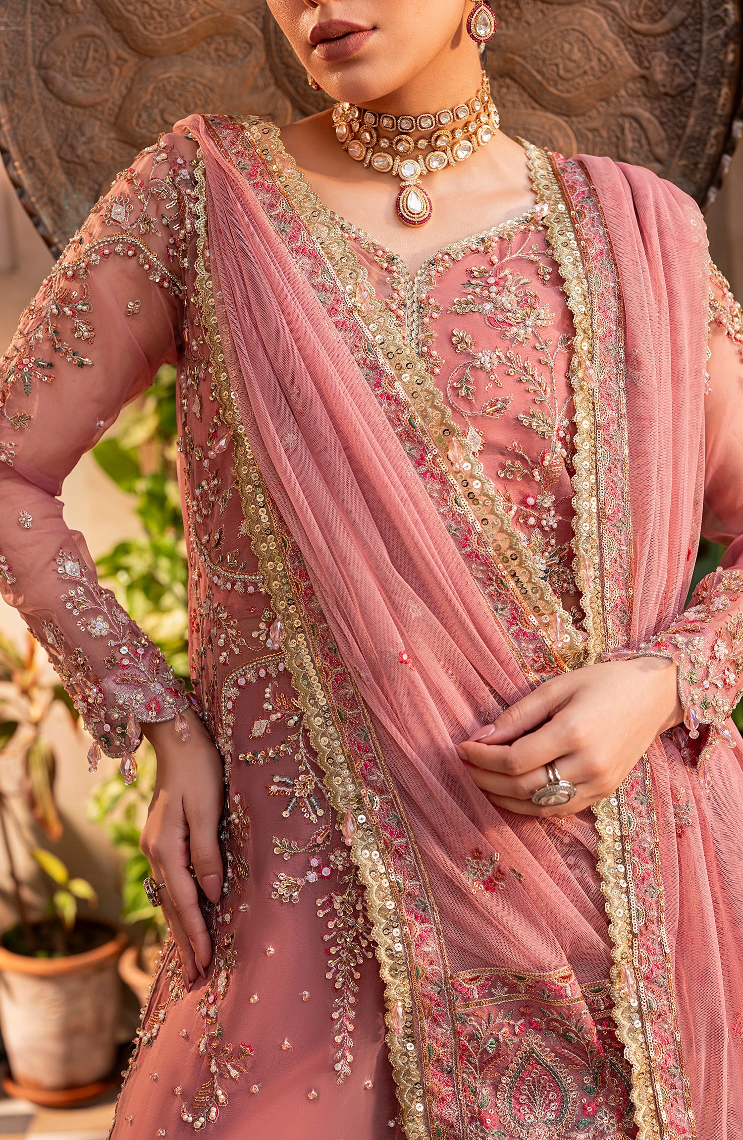 Person wearing a pink embroidered saree with intricate designs